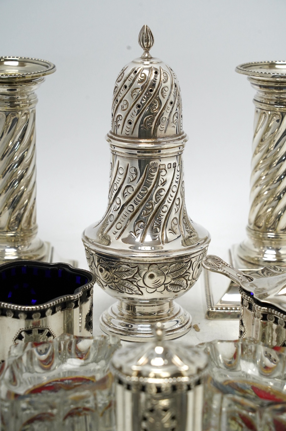 A 1970's silver sugar caster, a modern silver three piece condiment set, a silver oval dish and four other items including a pair of silver plated dwarf candlesticks. Condition - poor to fair
